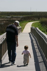 A_man_and_toddler_take_a_leisurely_walk_on_a_boardwalk